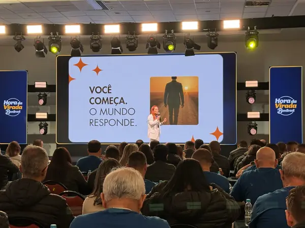 Carol no palco da Convenção Banco do Brasil, plateia com mãos levantadas