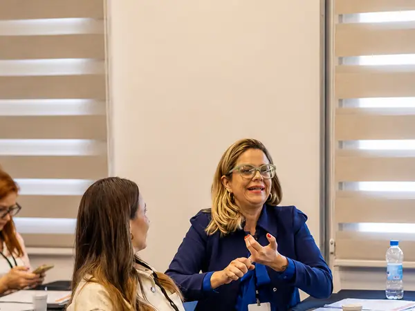 Carol conduzindo sessão de mentoria com lideranças em sala de reunião