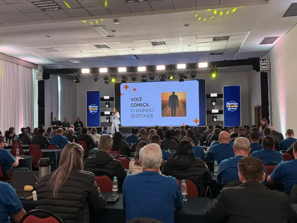 Palestra corporativa em grande auditório, visto do fundo